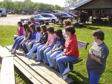 Girl scouts with leader watching horseback riding